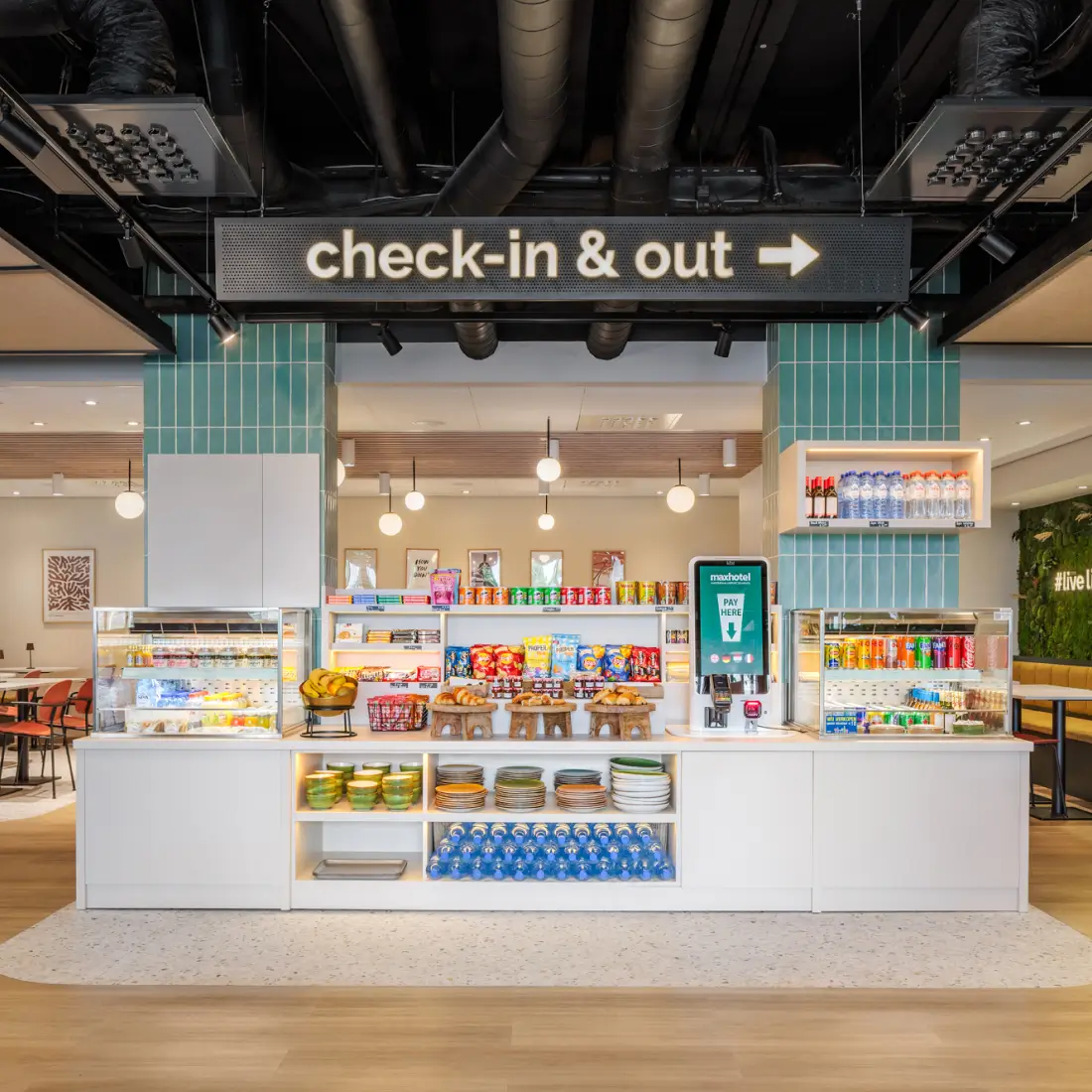 The Maxhotel check-in and out counter with snacks, drinks, and a self-service station.
